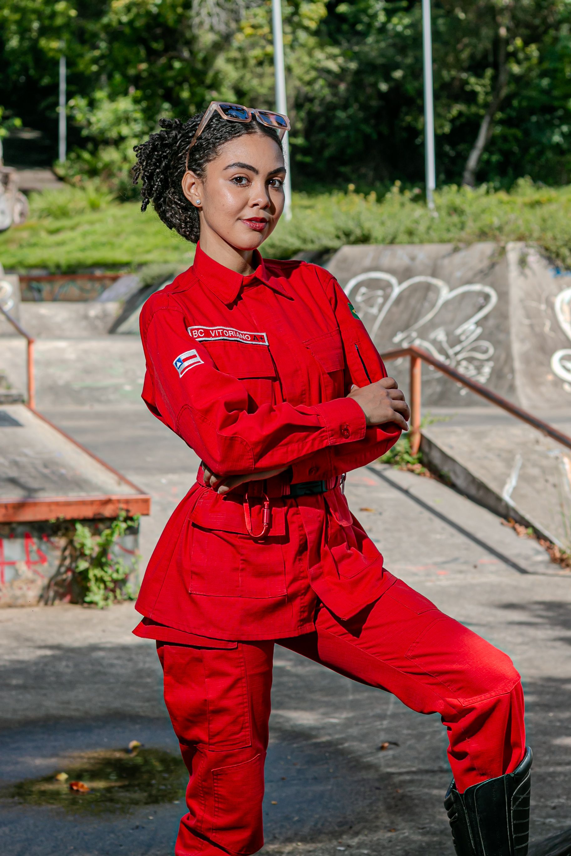 Confident woman in vibrant red uniform poses outdoors on a sunny day.