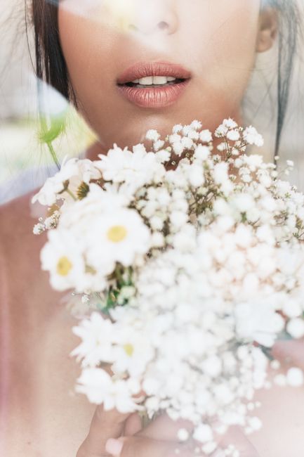 Close-up portrait of a woman holding a bouquet of white flowers, exuding elegance and natural beauty.