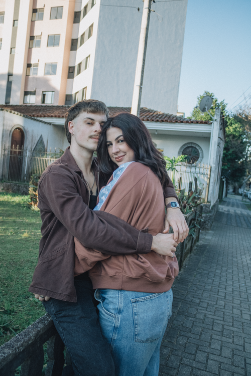 Free A young couple embraces affectionately outdoors against a city backdrop. Stock Photo