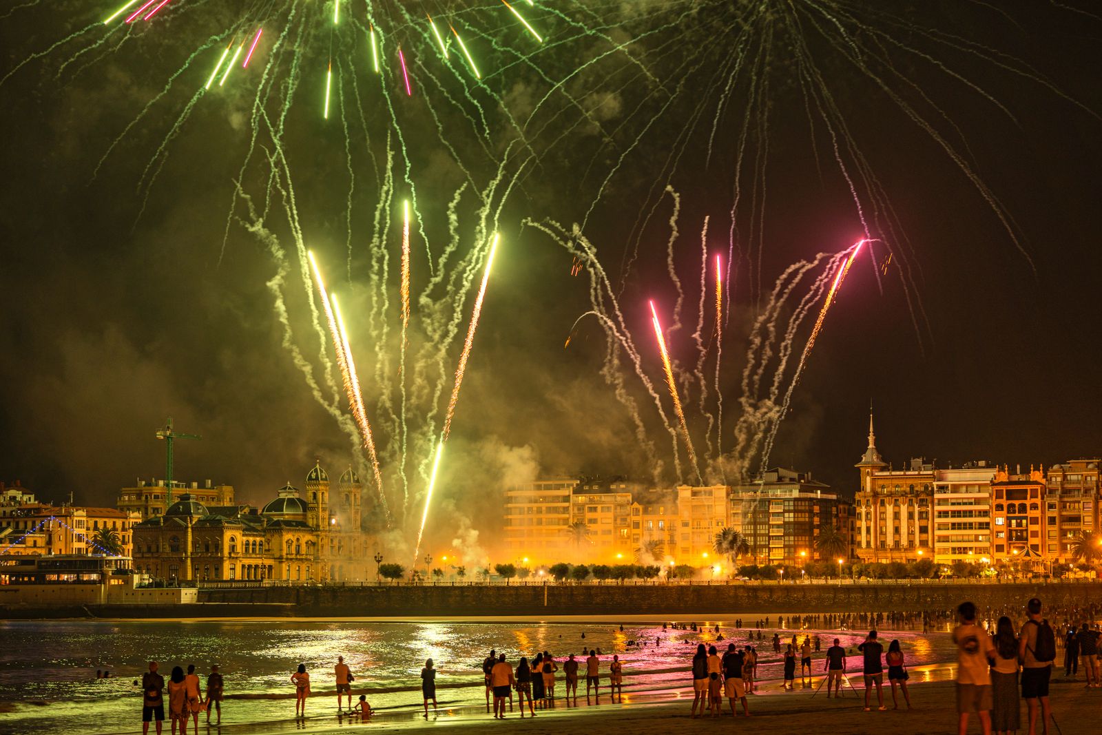 Fireworks illuminate the night sky over San Sebastián beach, creating a vibrant celebration atmosphere.