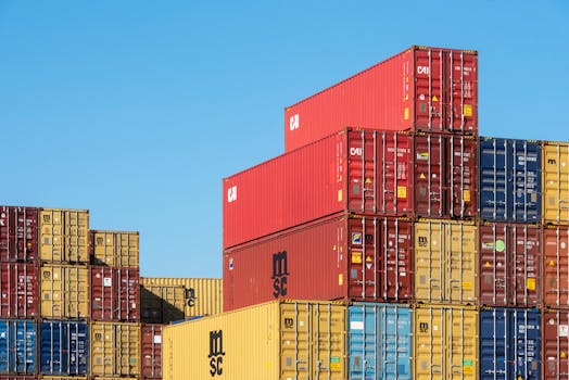 A vibrant collection of stacked shipping containers under a clear, blue sky. Ideal for logistic themes.