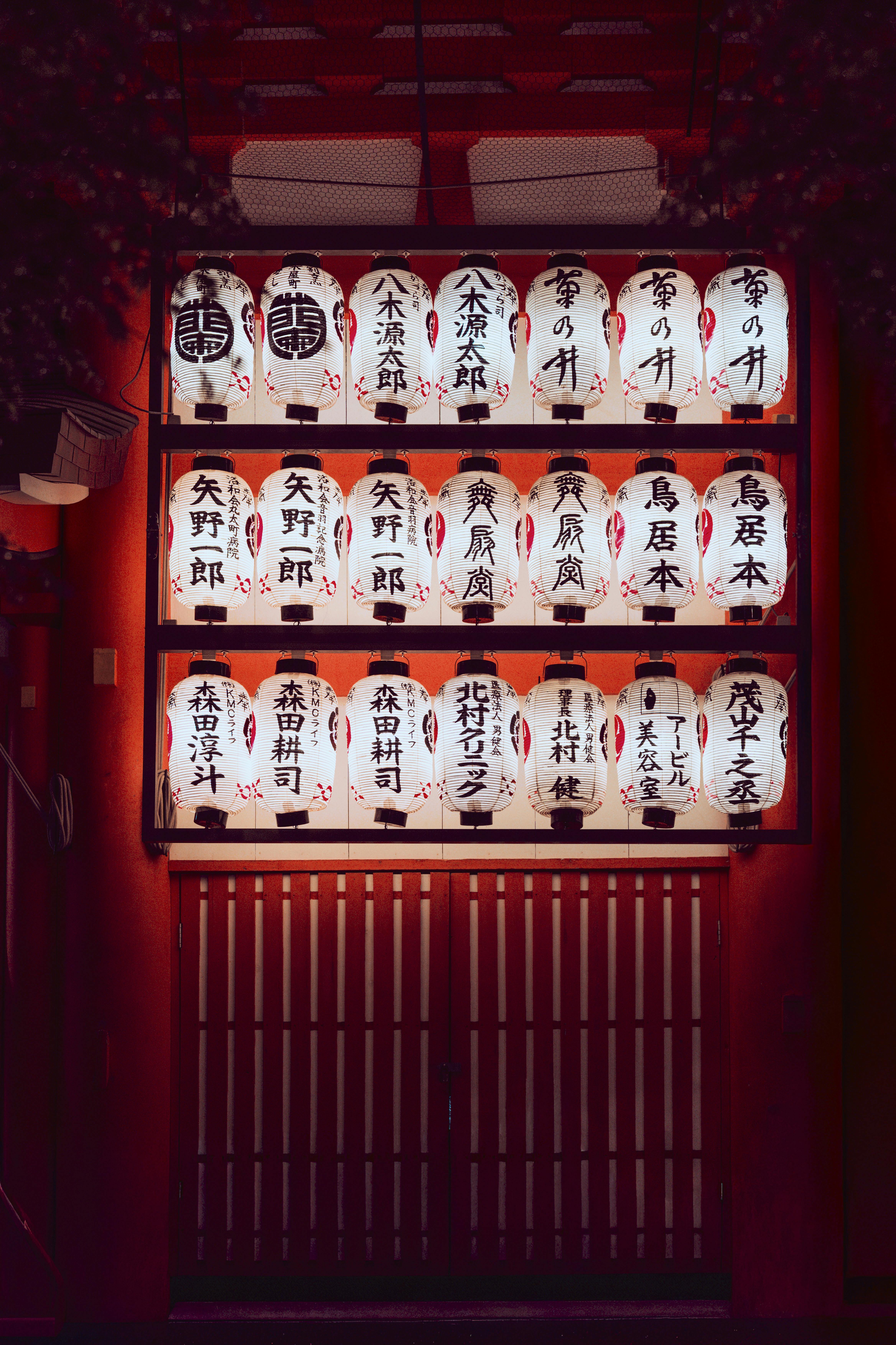 Illuminated Japanese paper lanterns at a shrine in Kyoto, Japan, glowing against red background.