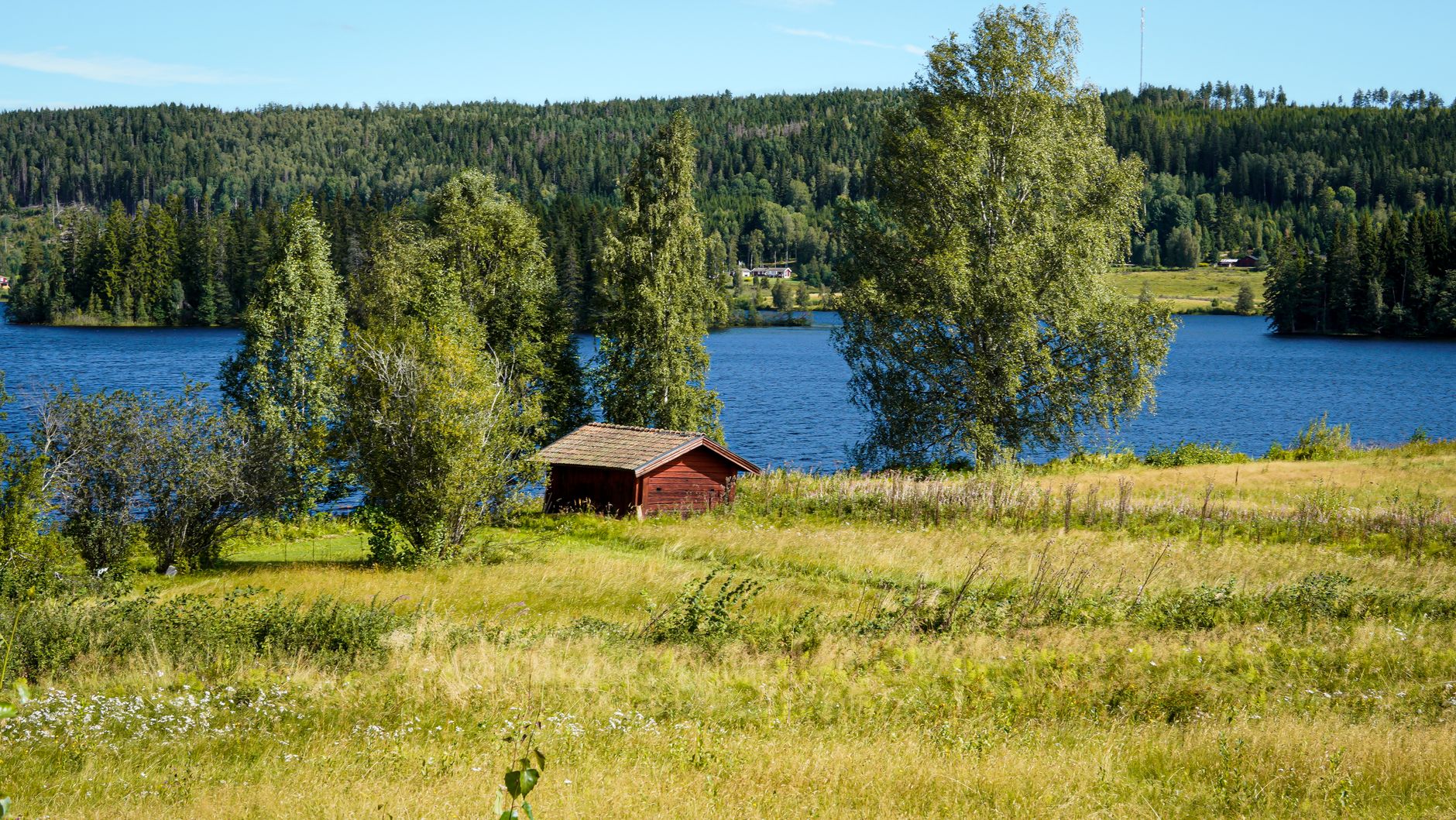 Scenic view of a cabin beside a lake in Värmland, Sweden; perfect for nature lovers.