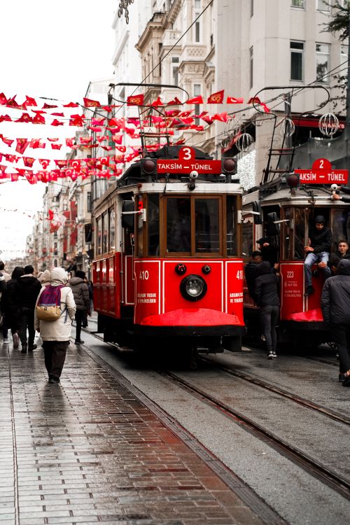 Free Iconic red tram on rainy Istiklal Street, Istanbul with bustling crowd. Stock Photo