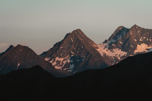 Majestic mountain peaks with snow patches during twilight calm.