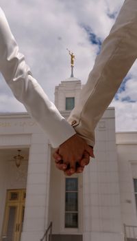 A couple holds hands in front of a temple, symbolizing unity and love.