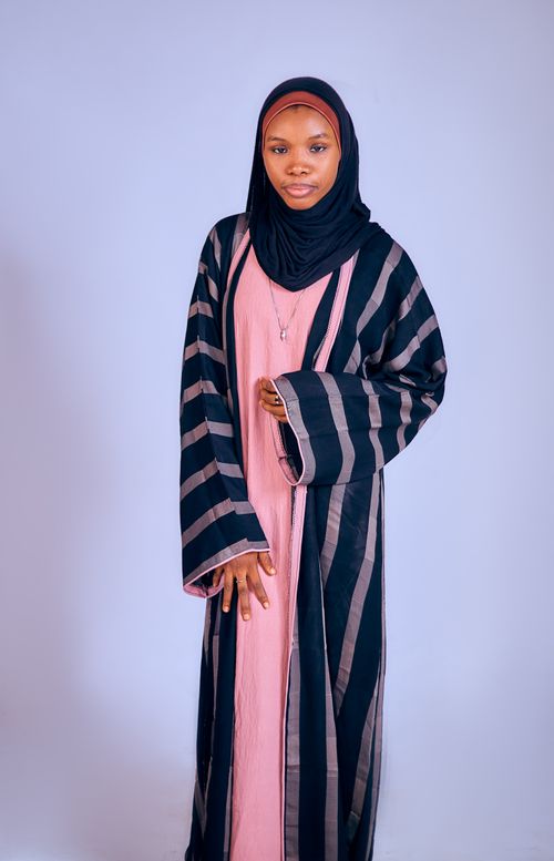 Free Portrait of a young woman in a stylish striped abaya and hijab, exuding grace and elegance. Stock Photo