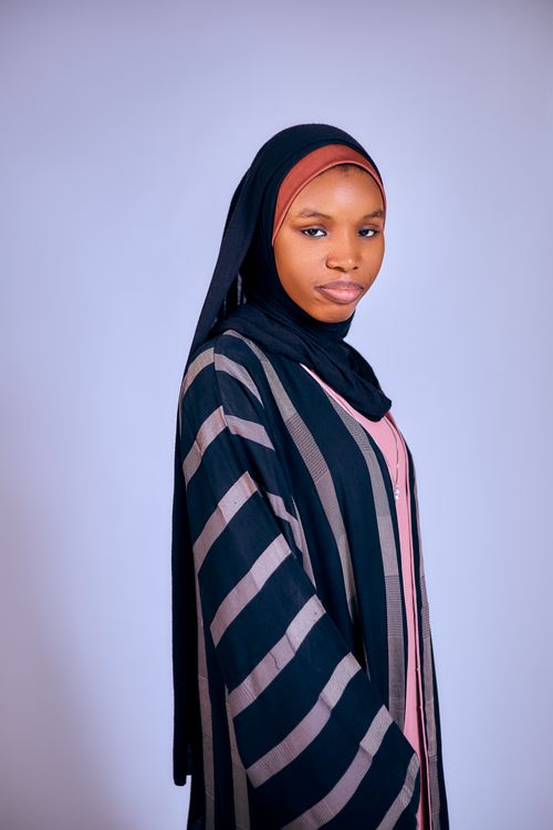 Free Elegant portrait of a woman wearing a striped abaya and hijab, highlighting cultural fashion Stock Photo