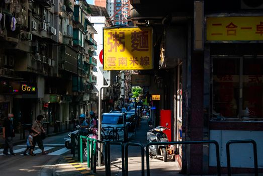 A busy street scene in a vibrant urban alleyway featuring prominent Chinese signage.