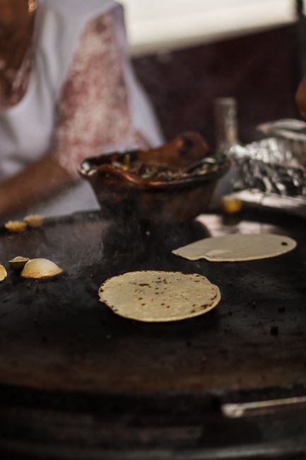 Two golden, griddle-marked flour tortilla quesadillas cut into wedges on a flat-top griddle, melted cheese and peppers visible at the cut edges.