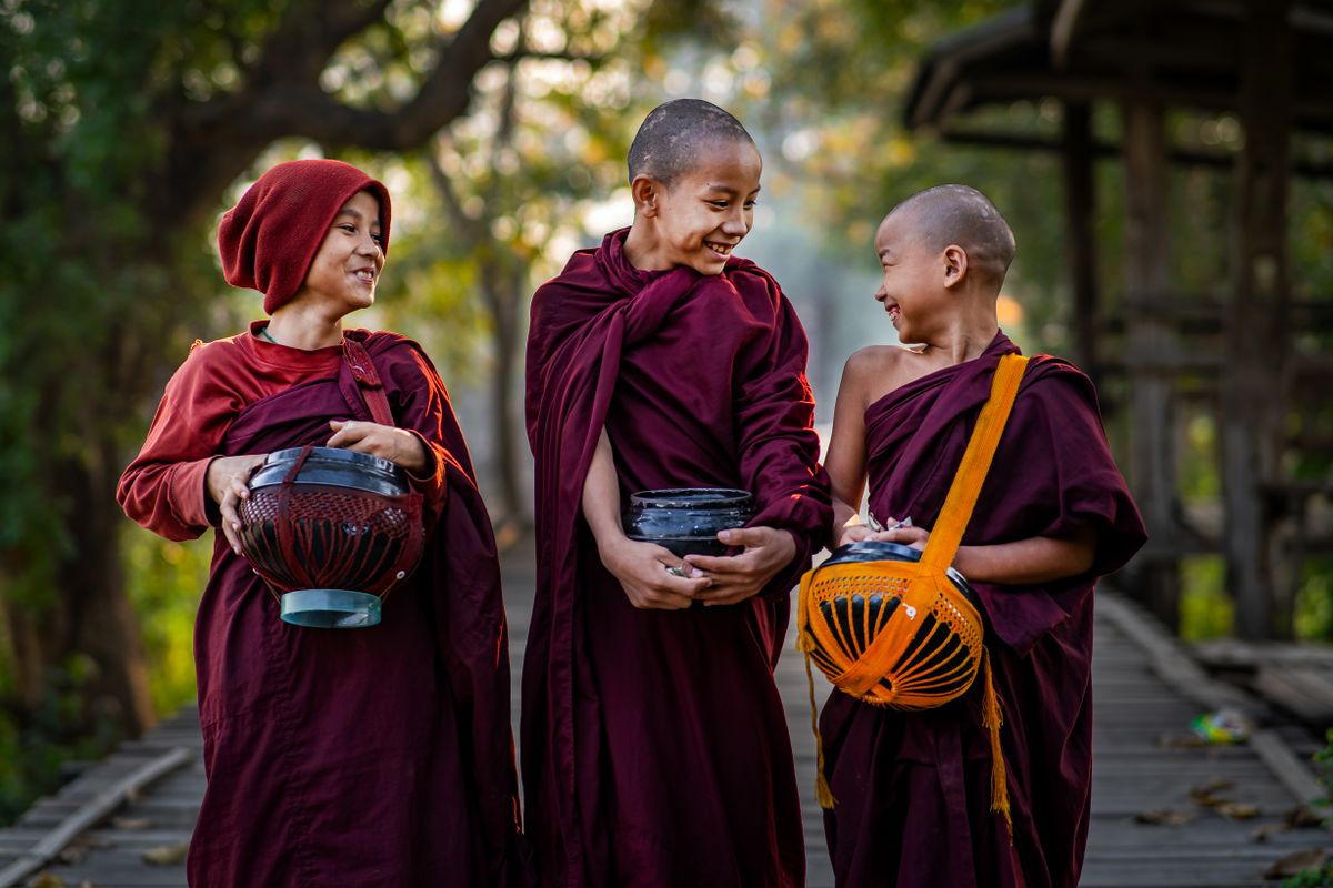 Young monks crossing U Bein bridge at sunrise