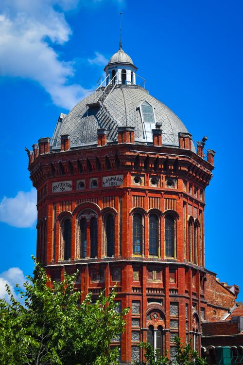 Free Majestic red brick dome against a vibrant blue sky with lush foliage. Stock Photo