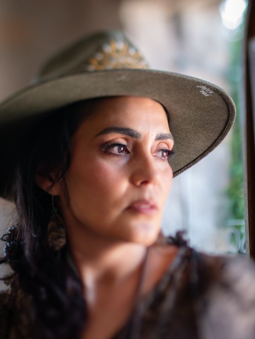 Free A contemplative woman in a stylish hat gazes out a window, ambient lighting. Stock Photo