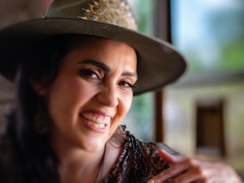 Free Portrait of a joyful woman wearing a hat, captured in soft, natural light indoors. Stock Photo