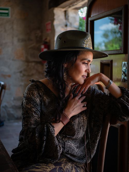 Free A thoughtful woman in traditional clothing and hat gazes out a rustic window. Stock Photo