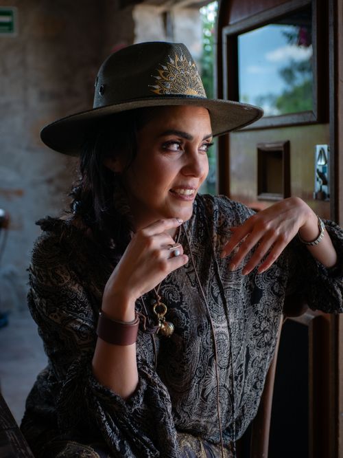 Free Woman in patterned outfit and hat sitting indoors, exuding style and relaxation. Stock Photo