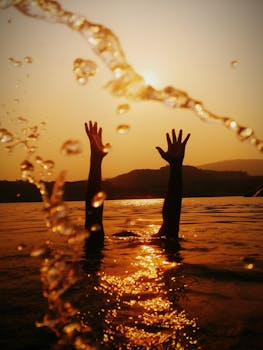 金色的日落中，剪影的手伸向天空，倒影在荡漾的水面上