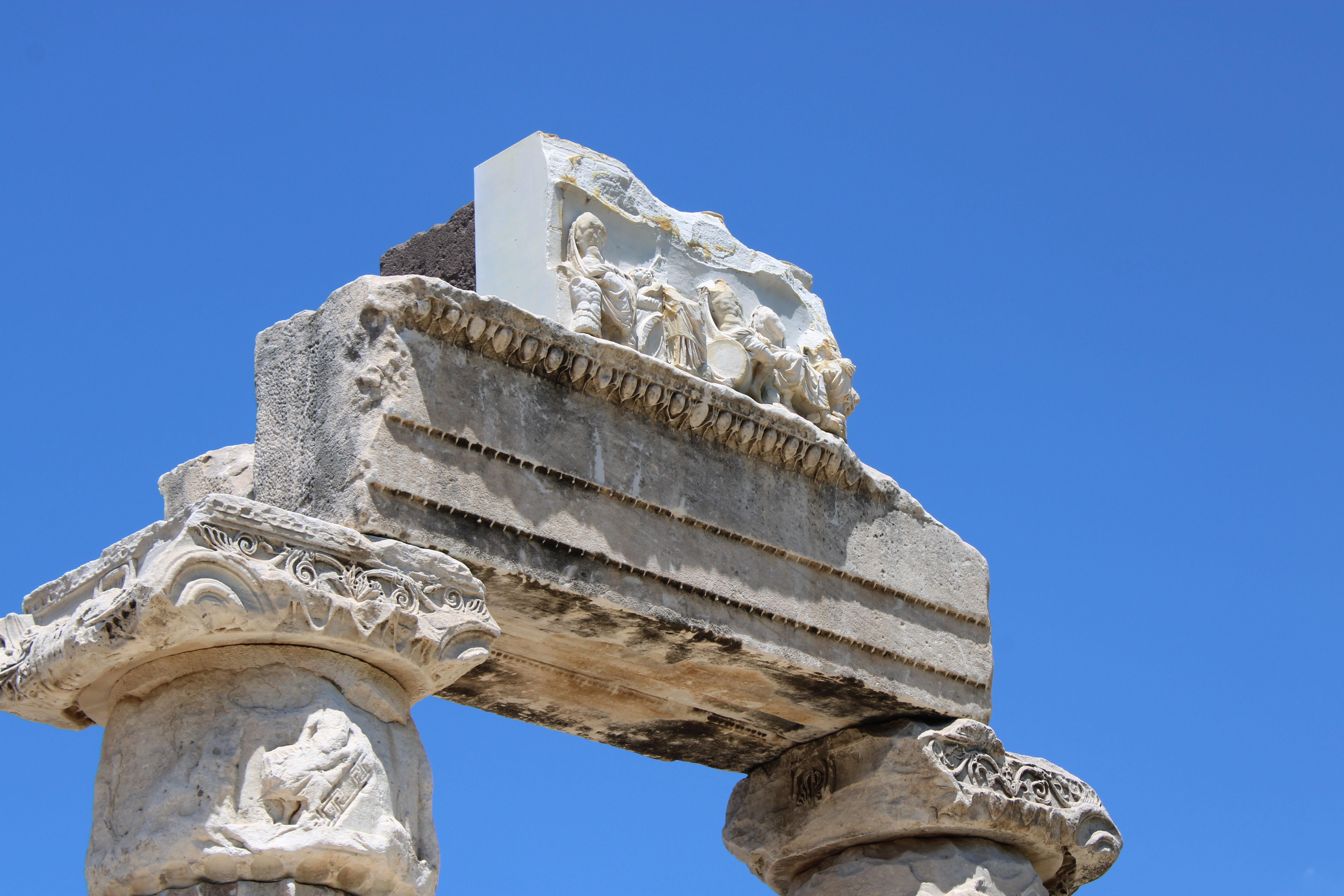 Une vue détaillée d'une ancienne arche en pierre avec des sculptures sur fond de ciel bleu vif.
