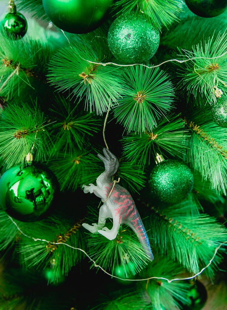 Close-Up Photo Of Christmas Tree With Green Baubles And Dinosaur Toy