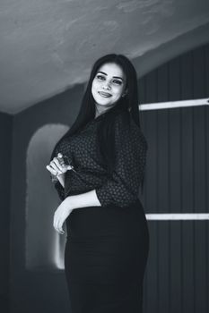 Black and white portrait of an elegant woman indoors showcasing vintage style fashion and poise.