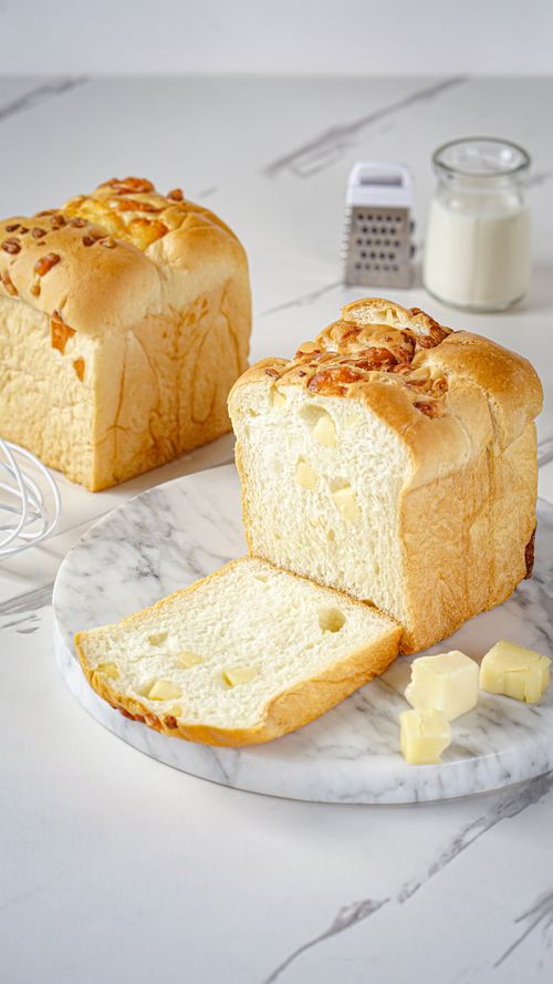 Free Delicious sliced cheese bread with cheese cubes on marble board, perfect for breakfast or snack. Stock Photo