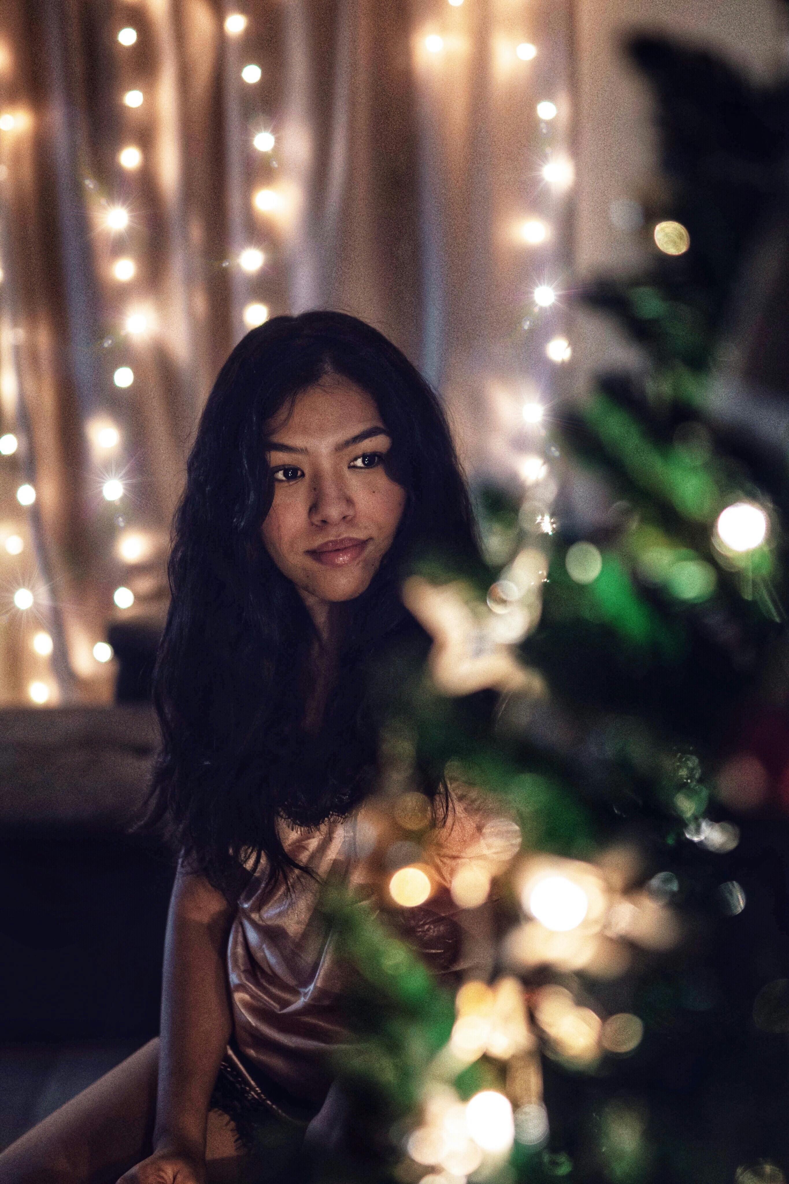 温暖的圣诞灯和装饰品包围着一位女性，营造出舒适的节日氛围