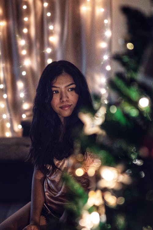 Woman Standing Beside Christmas Tree With String Lights