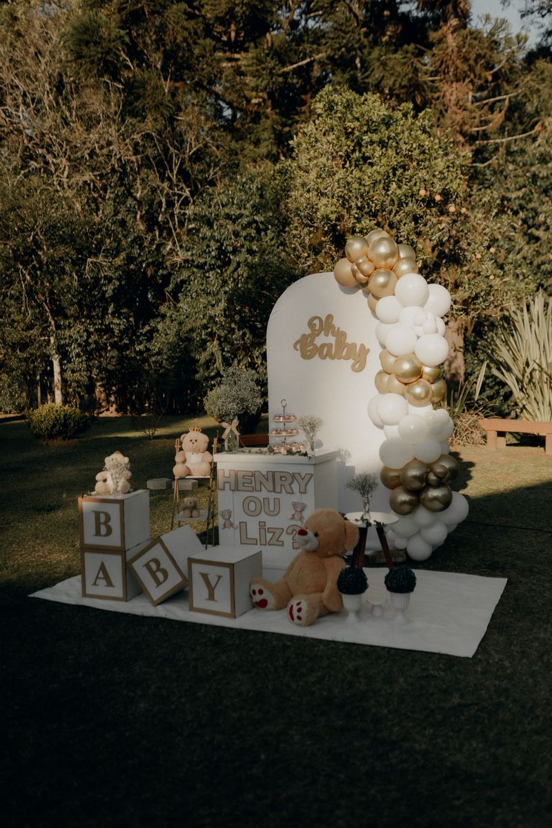 Elegant outdoor baby shower setup with gold and white balloons, plush toys, and baby-themed decorations.