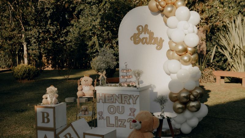 Elegant outdoor baby shower setup with gold and white balloons, plush toys, and baby-themed decorations.