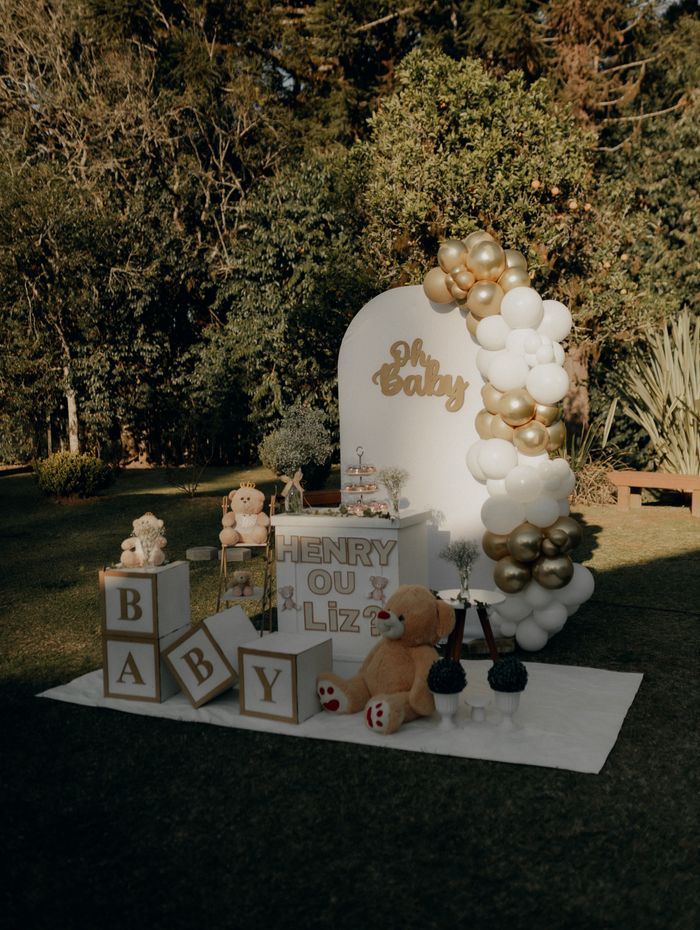 Gold and white baby shower balloon setup with plush toys