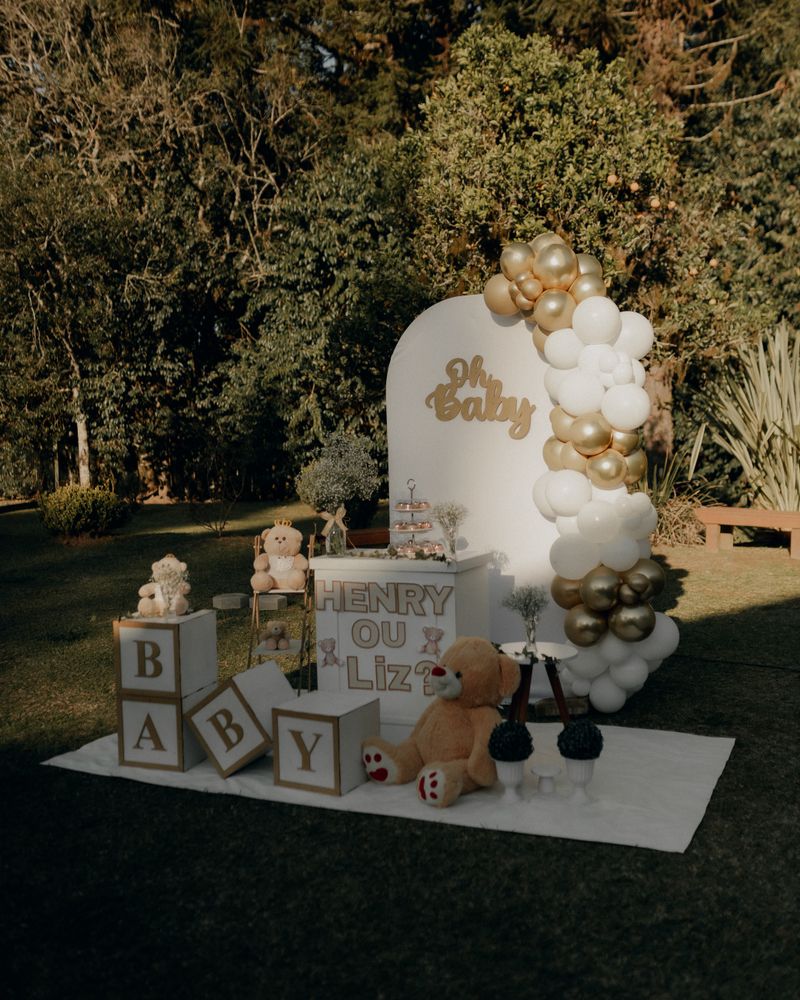 Baby shower setup with gold and white balloons and plush toys