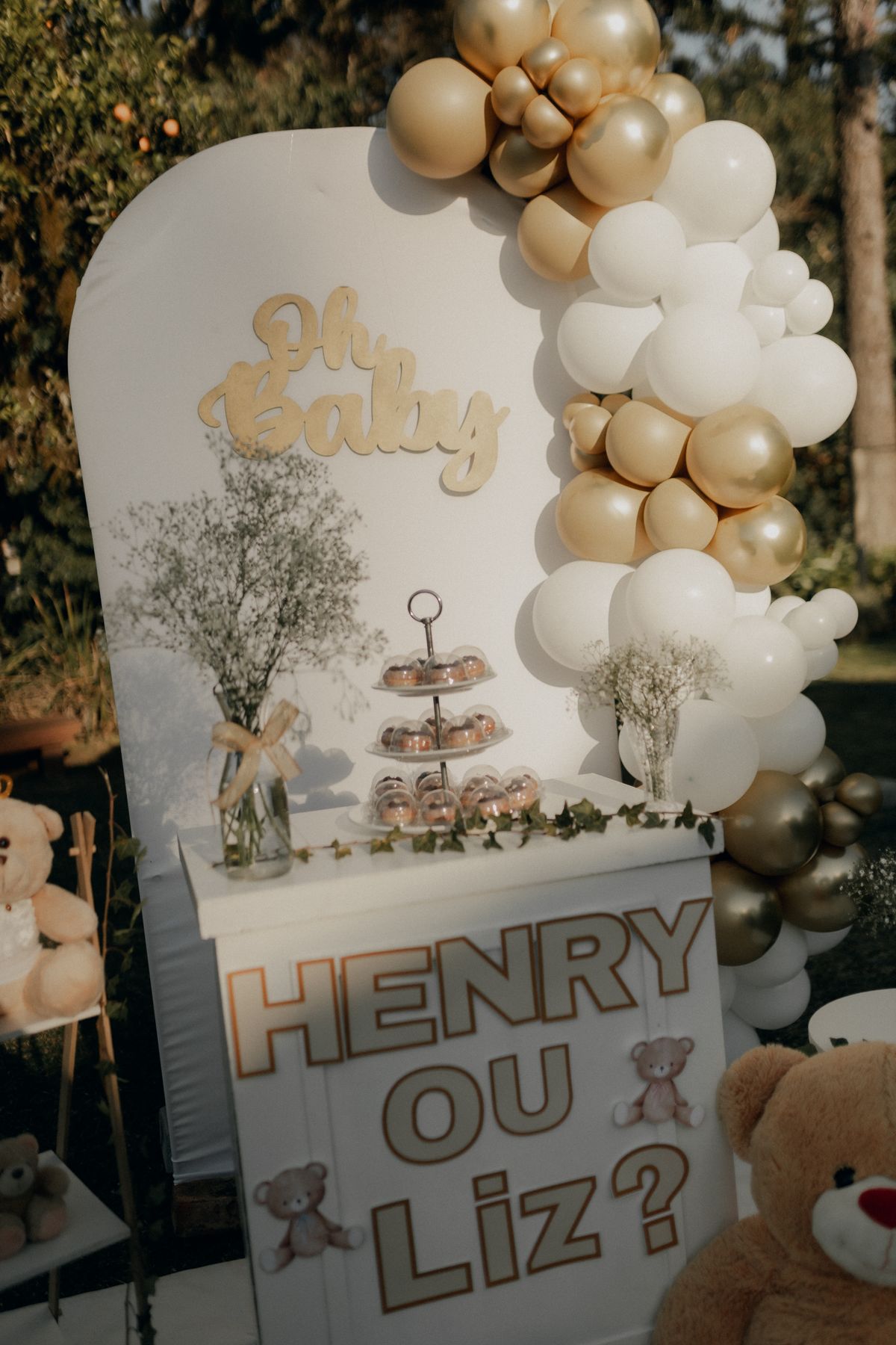 Outdoor Gender Reveal Dekoration mit weißen und goldenen Ballons im Garten