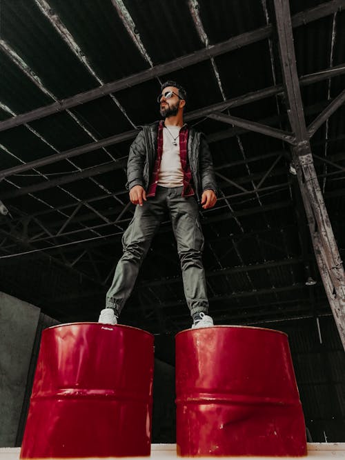 Man Looking at His Right While Standing on Two Metal Drums