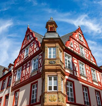 Beautiful historic half-timbered building in Coblenz, Germany with red accents and blue sky.