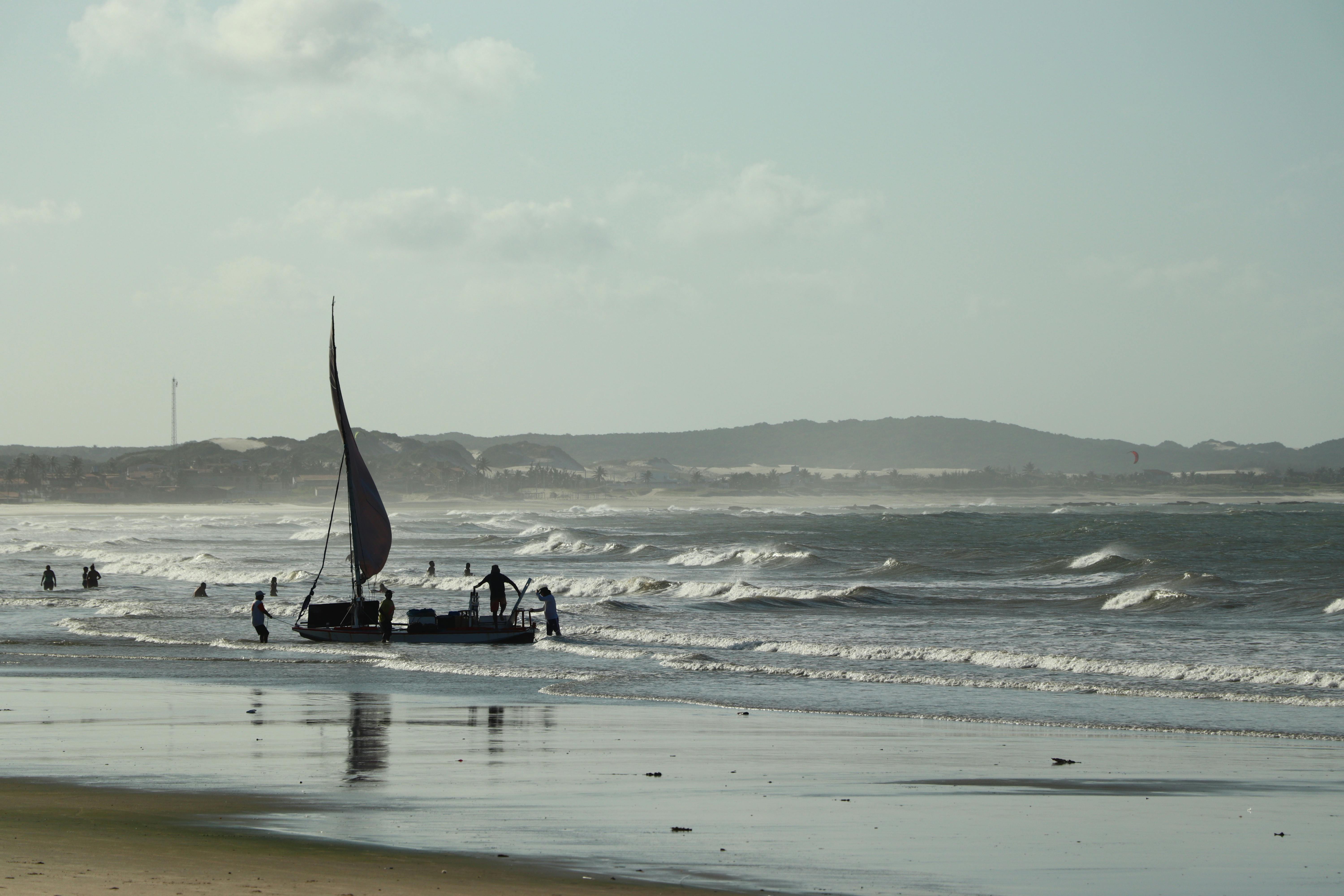 Sailboat and people enjoying a sunny day at a beach in Rio Grande do Norte, Brazil.