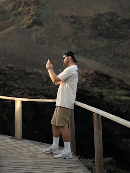 A man captures the volcanic landscape from a boardwalk in the Galapagos Islands.