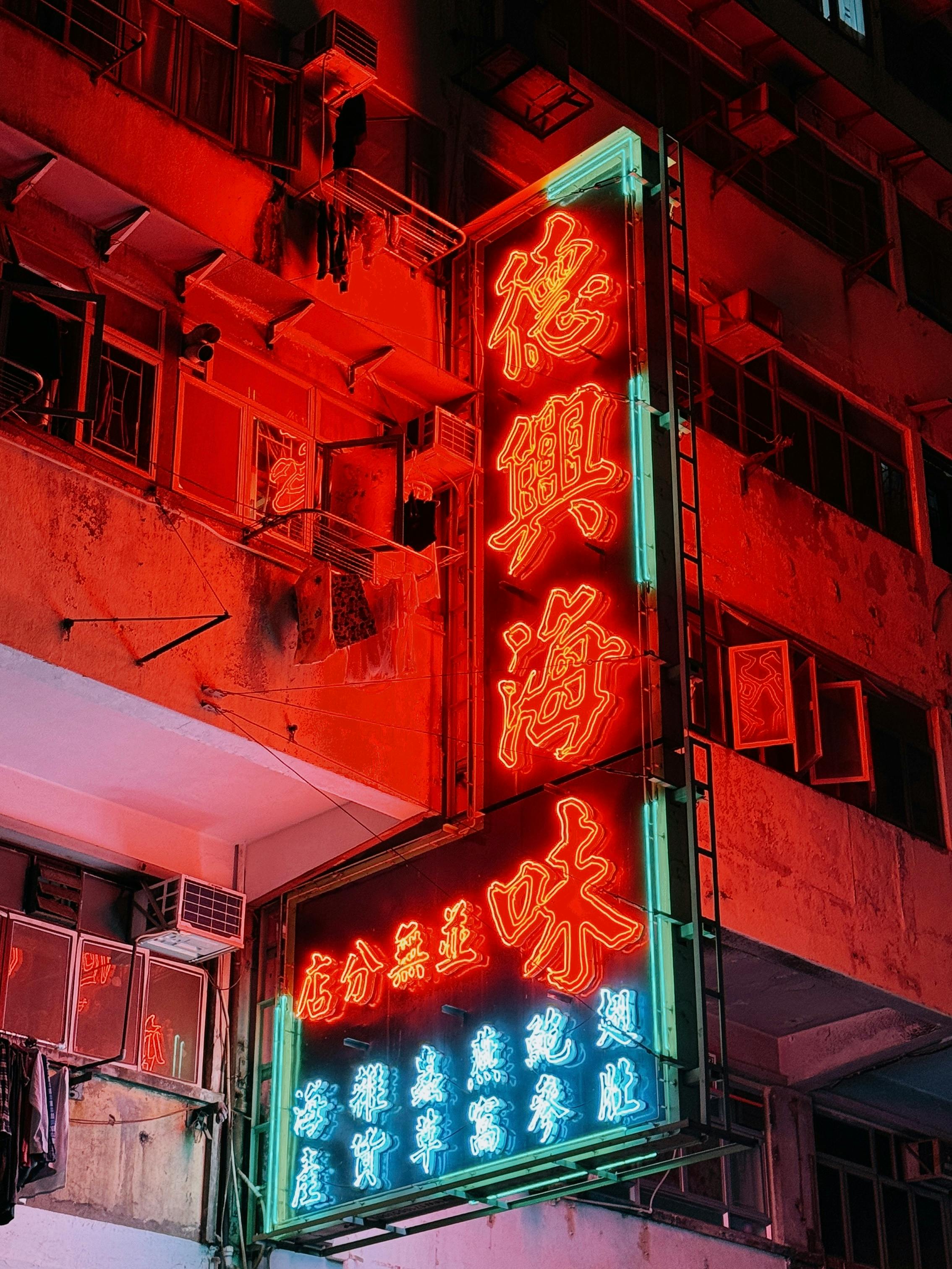 Captivating neon sign illuminating a building facade in Hong Kong's bustling street at night.