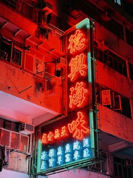Captivating neon sign illuminating a building facade in Hong Kong's bustling street at night.