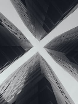Black and white perspective of soaring skyscrapers seen from below, forming an 'X' shape.