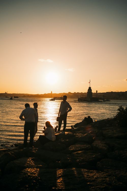 Free Silhouetted people by the sea at sunset, with Maiden's Tower in the distance, Istanbul view. Stock Photo