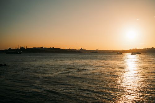 Free A serene sunset view over the Bosphorus Strait with boats and city skyline in silhouette. Stock Photo