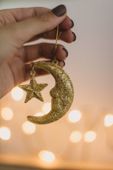 一只手握着带有温暖背景的星饰和闪闪发光的金色新月
