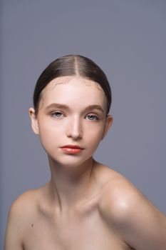 A close-up studio portrait of a young woman with natural makeup and a neutral expression.