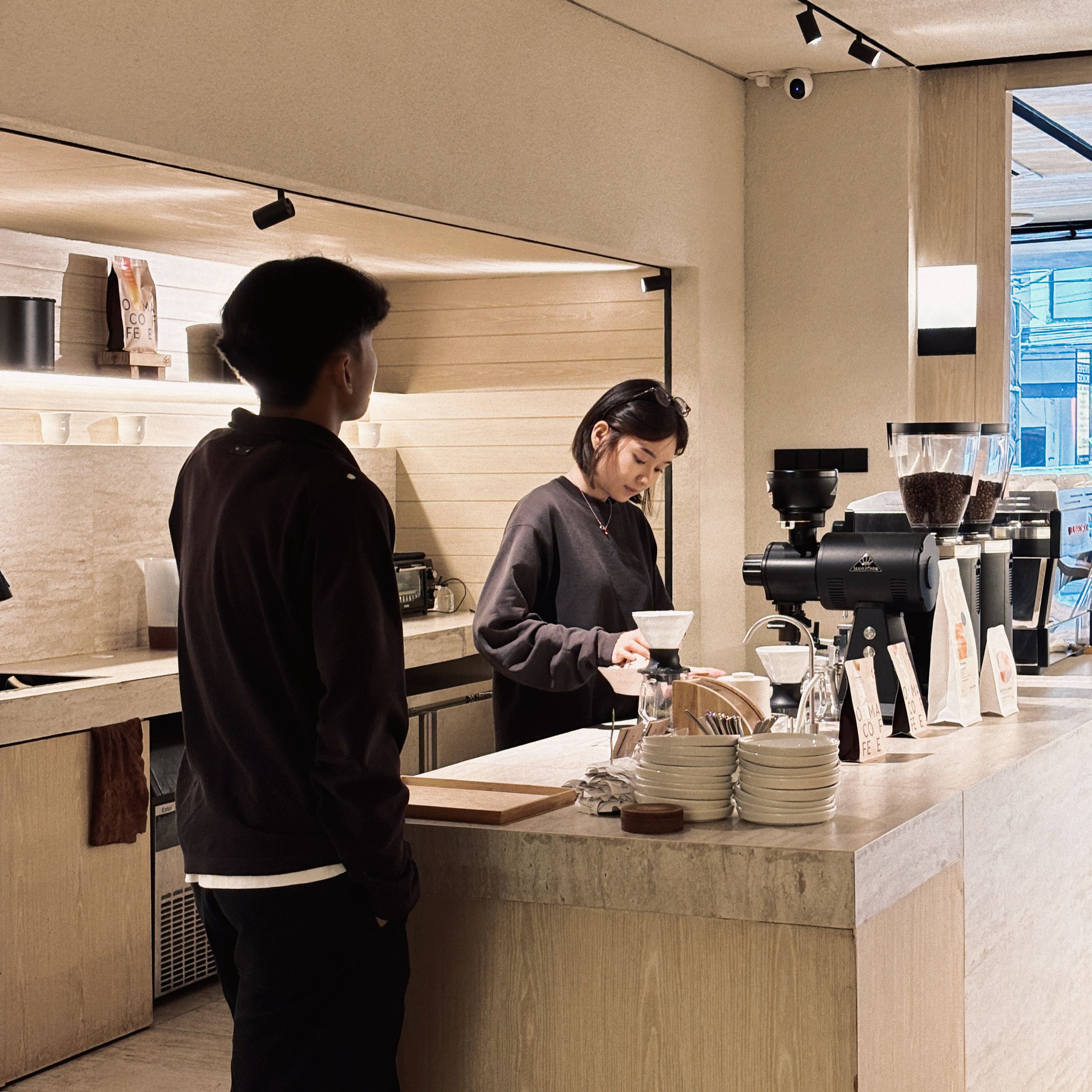 A barista prepares coffee for a customer in a modern, cozy coffee shop in Jakarta, Indonesia.