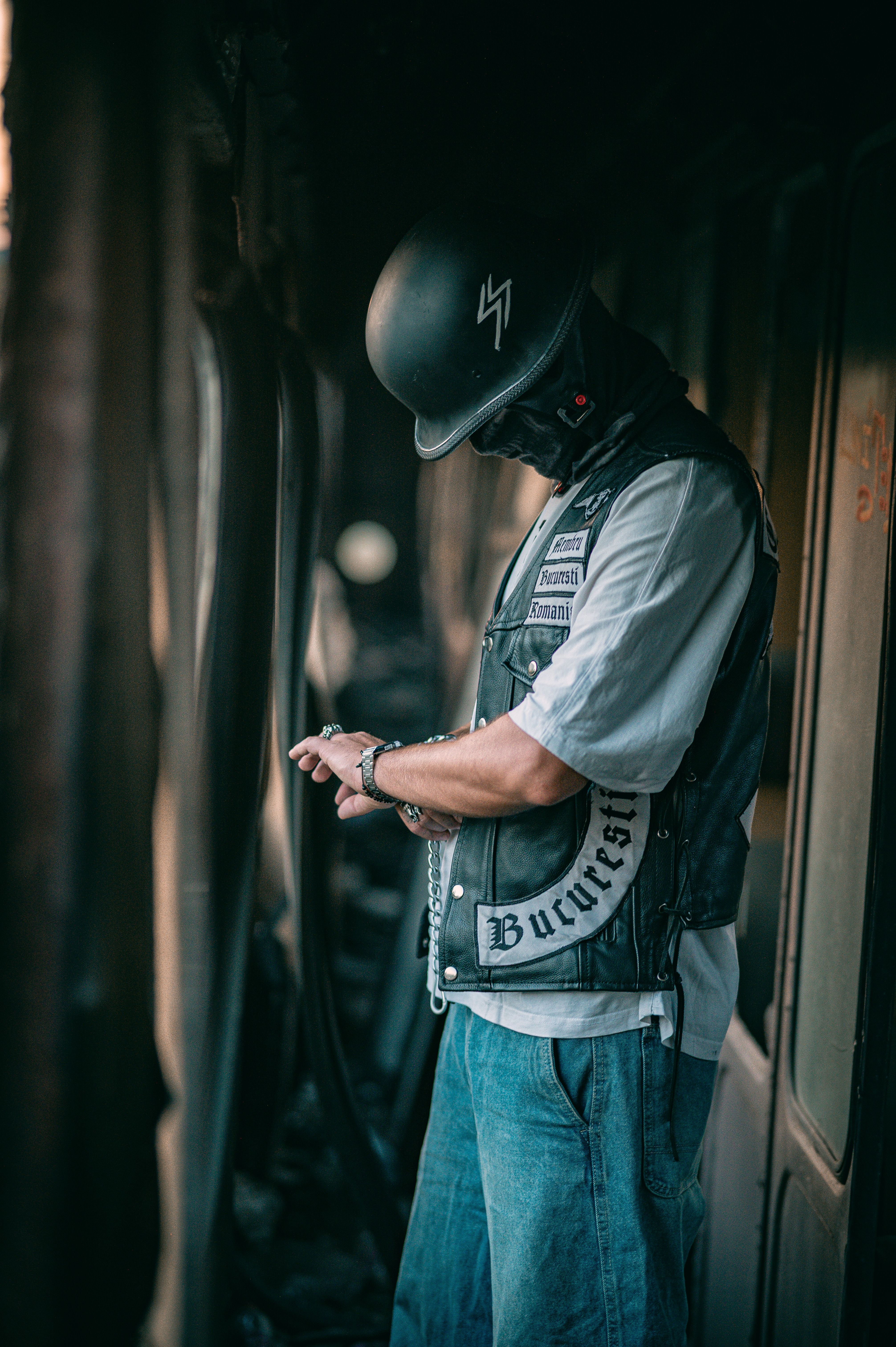 Side view of a man in a leather vest and helmet standing in a train, creating a vintage feel.