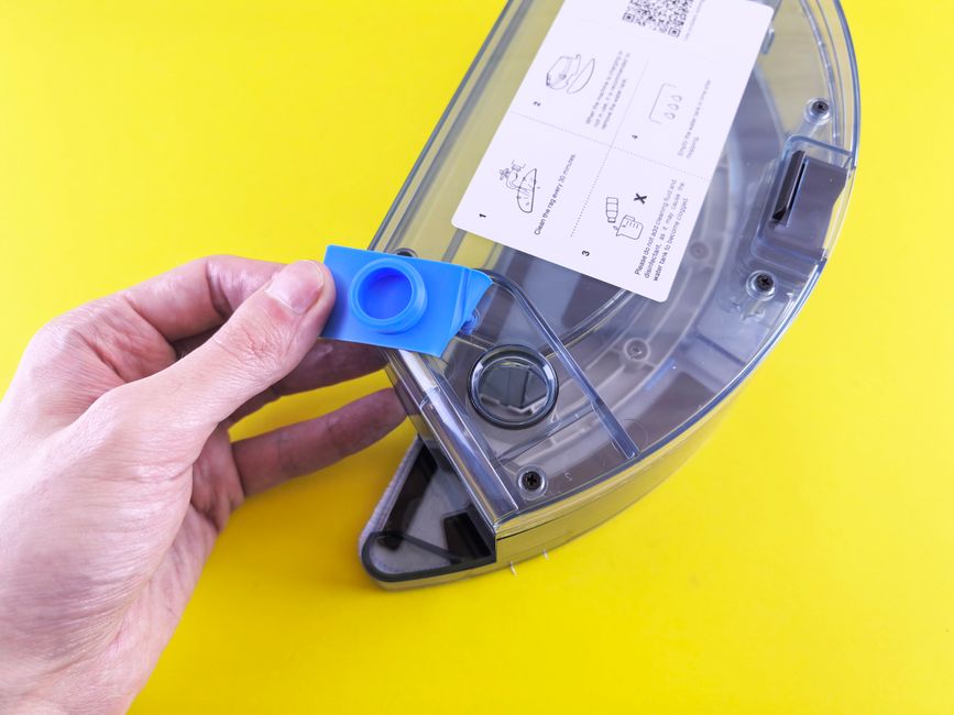 Top Robot Mop and Vacuum Combos for Hard Floors (2025 Review) Close-up of a person holding a vacuum cleaner water tank with a yellow background.