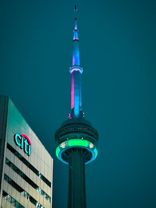 Free Colorful night view of CN Tower in Toronto, illuminated with vibrant lights against a dark sky. Stock Photo