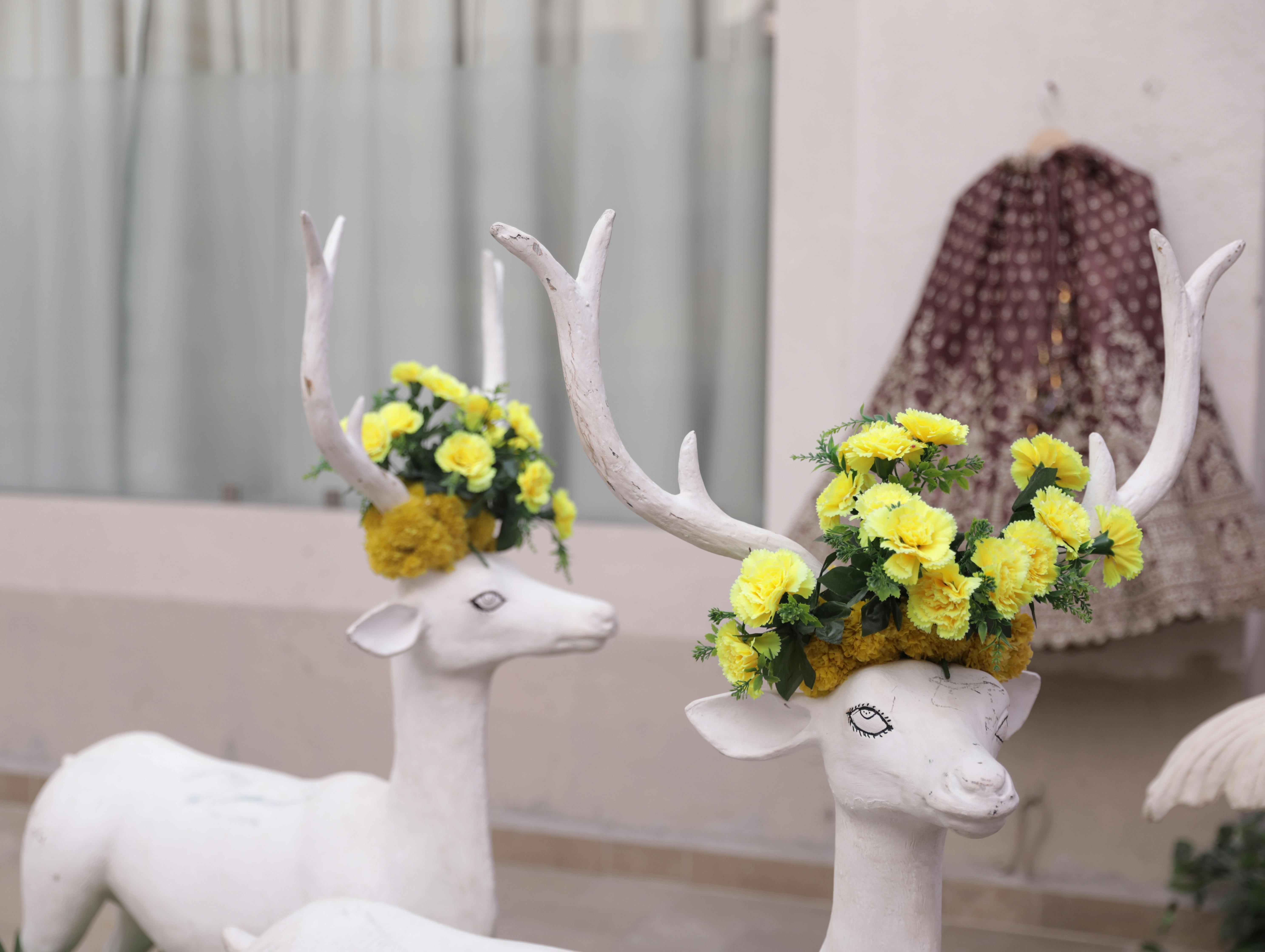 Elegant Indian wedding decor with deer sculptures adorned with yellow flowers.
