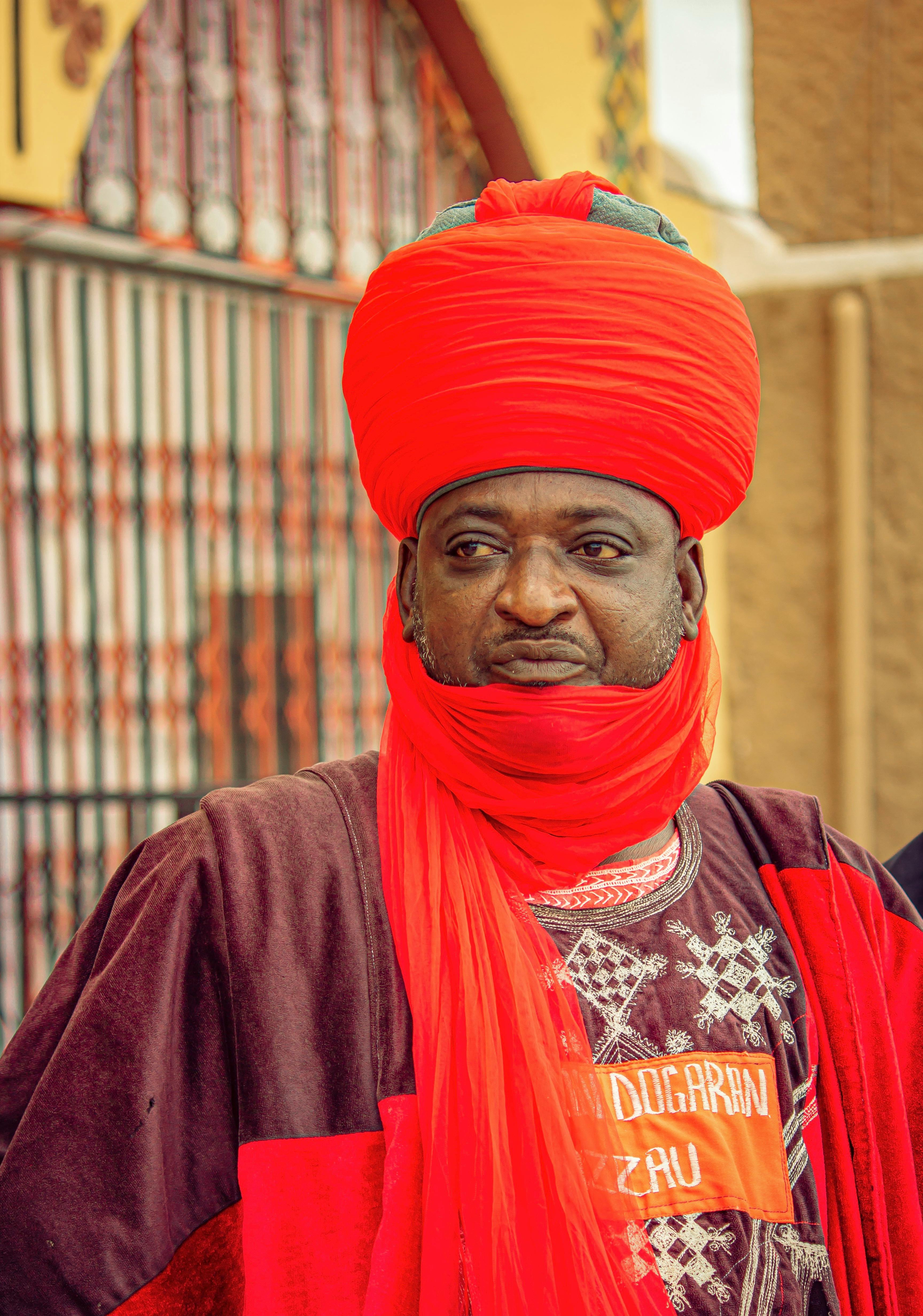 A Nigerian chief in Zaria City, wearing vibrant red traditional attire.