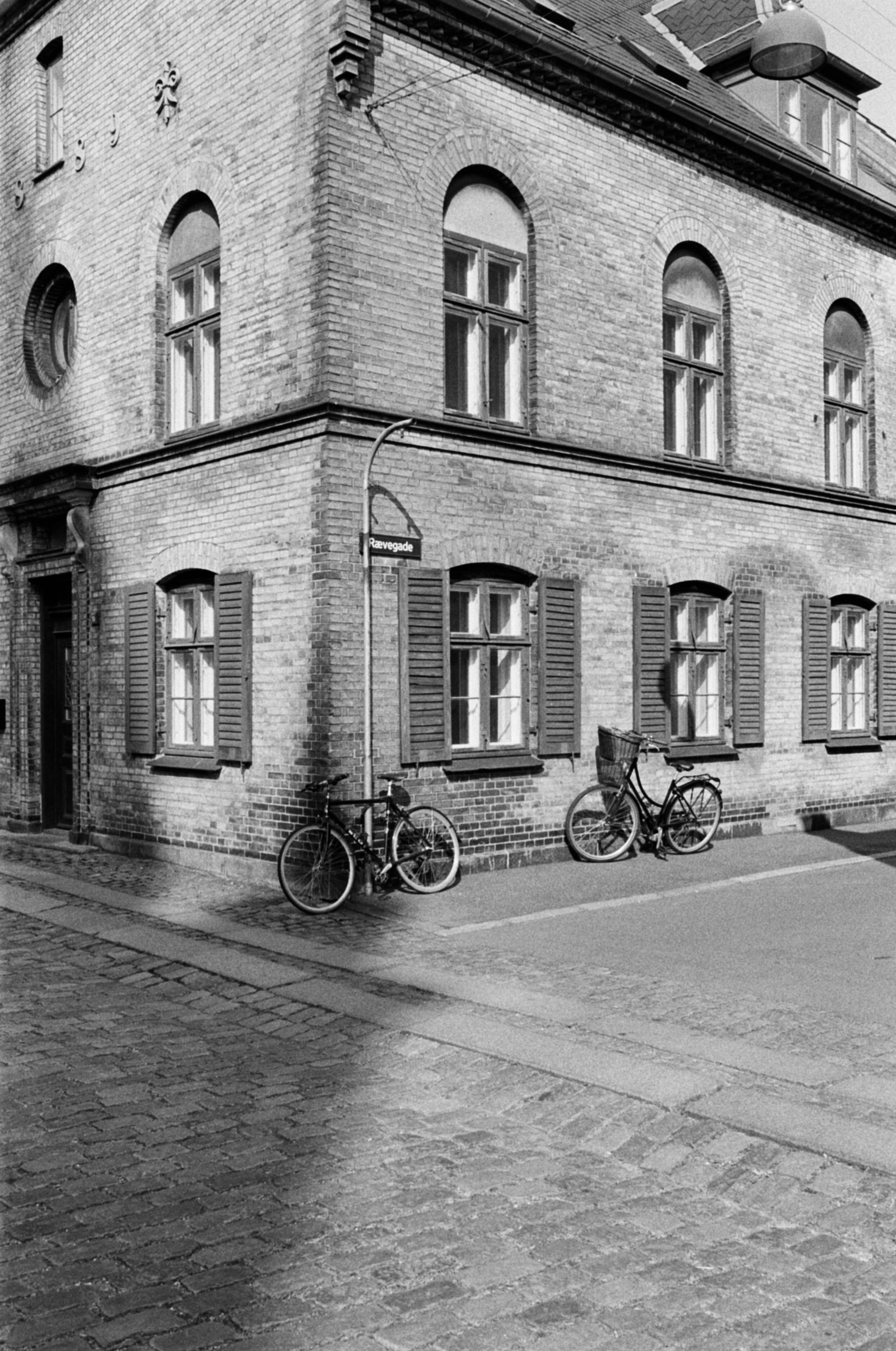 An atmospheric black and white photo of a vintage street corner with bicycles in Copenhagen, Denmark.